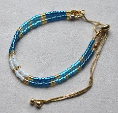 Armband 2 snoertjes 3mm Miyuki kralen blauw, wit en goud met schuifknoop