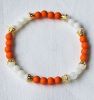 Armband 6mm acryl kralen oranje, wit en goudkleur